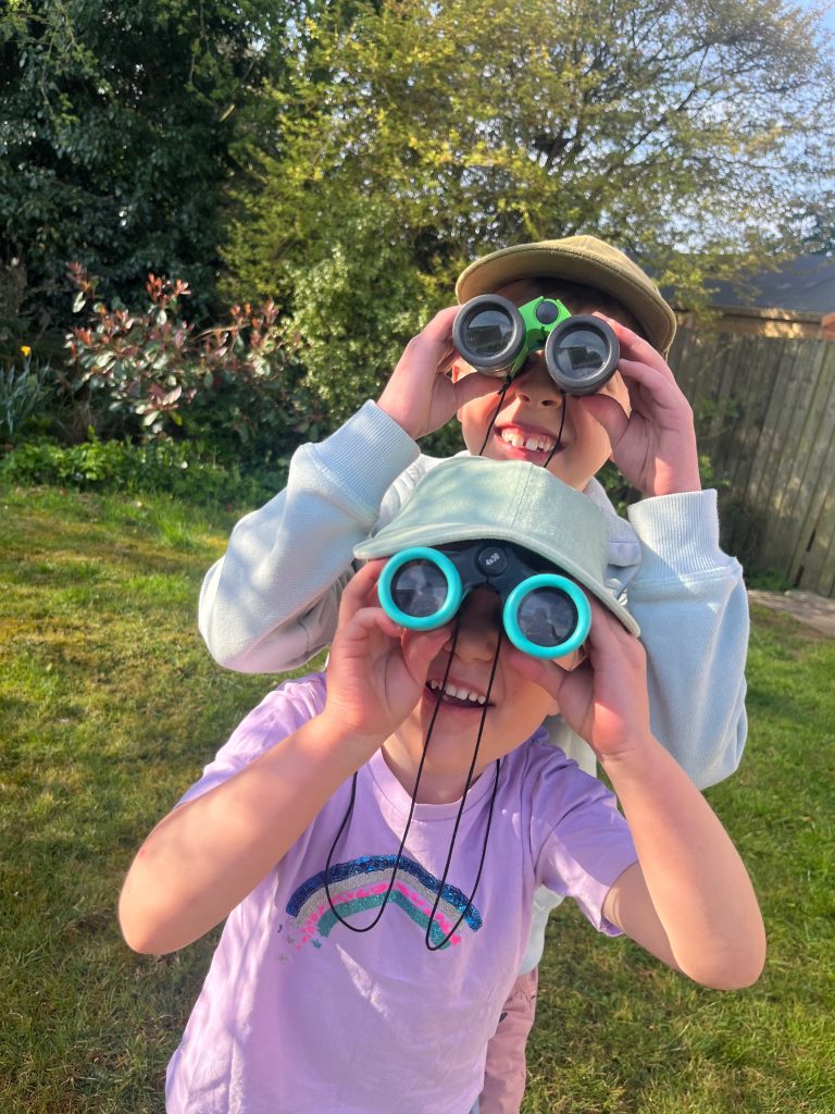 a girl and a boy looking through binoculars looking for birds